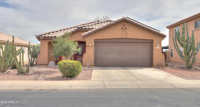 mediterranean / spanish-style home with stucco siding, a tiled roof, concrete driveway, and a garage