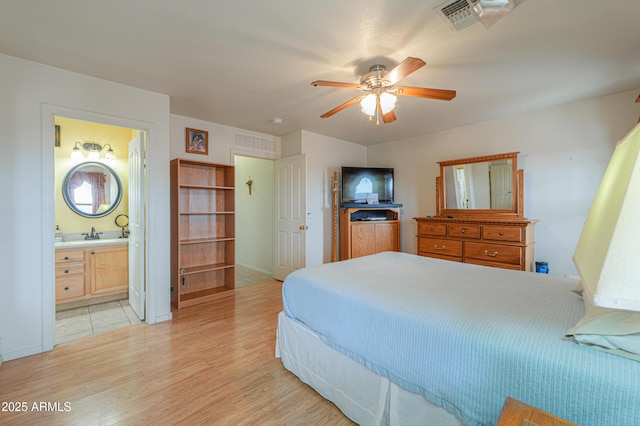 bedroom featuring light wood-style flooring, a ceiling fan, visible vents, and a sink