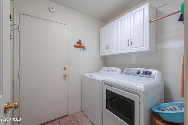 laundry area featuring light tile patterned floors, cabinet space, and washer and clothes dryer