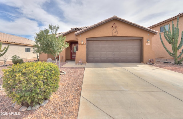 mediterranean / spanish house featuring concrete driveway, a tiled roof, an attached garage, and stucco siding