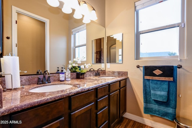 bathroom with double vanity, a sink, baseboards, and wood finished floors