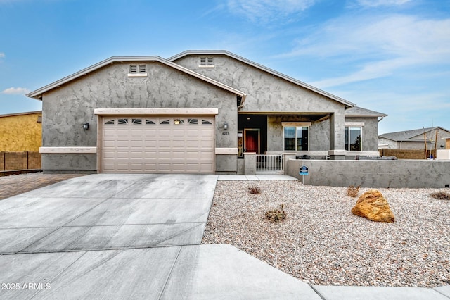 view of front of home with an attached garage, fence, concrete driveway, and stucco siding