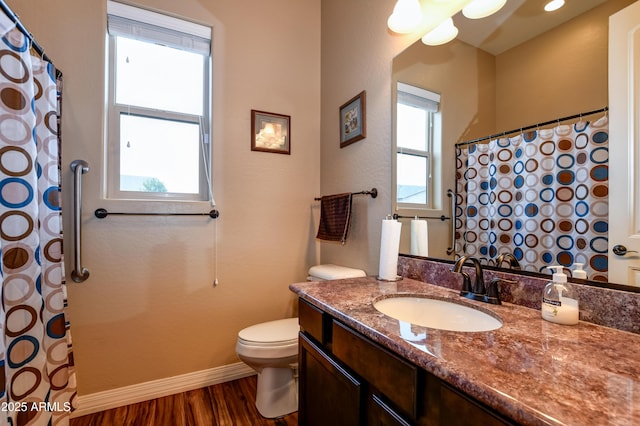 bathroom with a wealth of natural light, baseboards, toilet, and wood finished floors