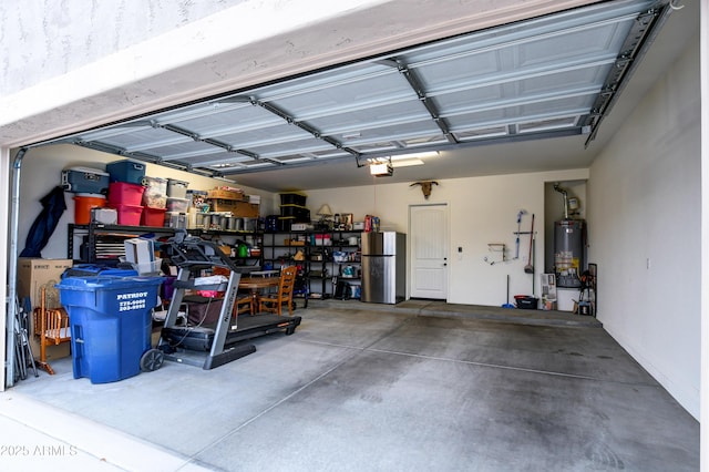 garage with a garage door opener, freestanding refrigerator, and gas water heater