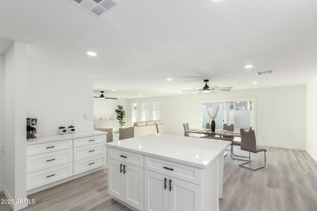 kitchen with light stone counters, recessed lighting, visible vents, light wood-style flooring, and white cabinets