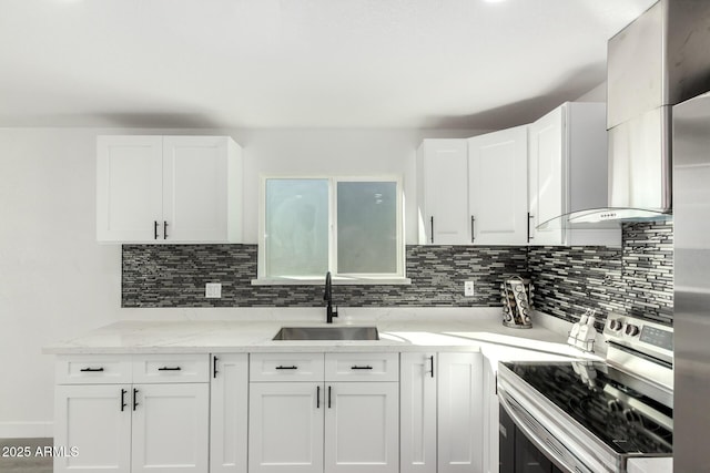 kitchen featuring wall chimney exhaust hood, stainless steel electric range, white cabinets, and a sink