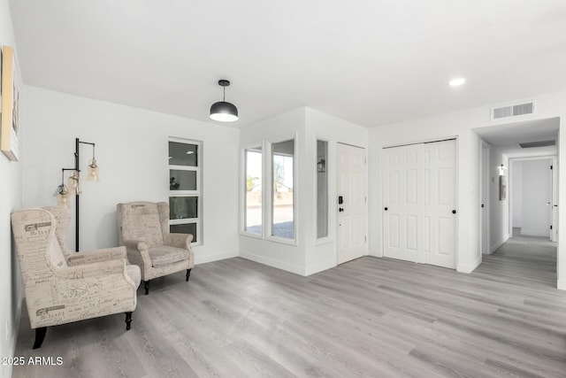 living area with recessed lighting, light wood-type flooring, visible vents, and baseboards