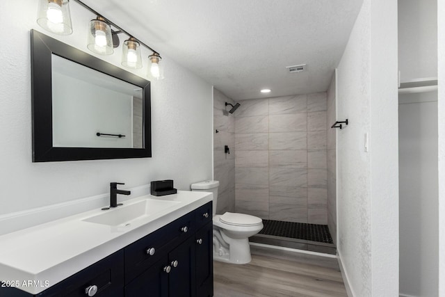 bathroom with a stall shower, visible vents, toilet, wood finished floors, and vanity