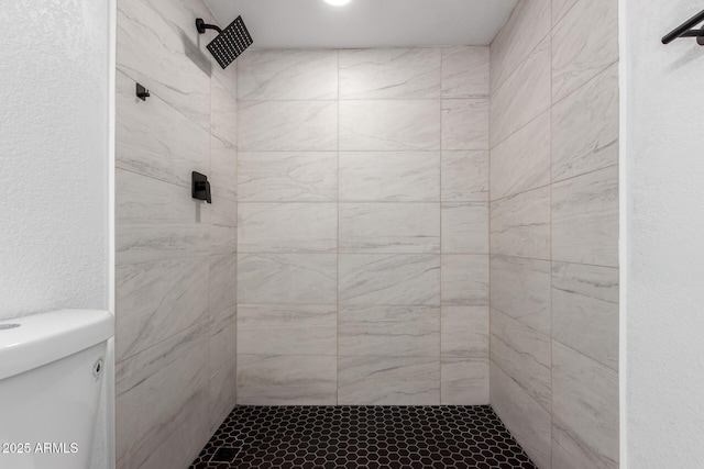 bathroom featuring a tile shower and toilet