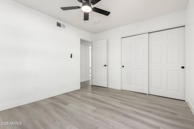 unfurnished bedroom featuring light wood-style floors, a closet, visible vents, and baseboards