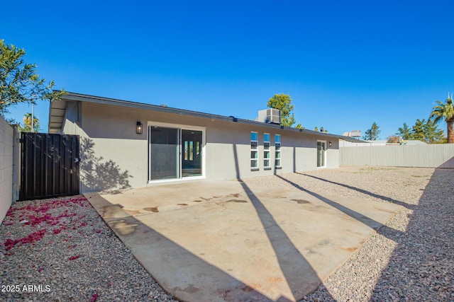 back of house featuring central AC, a patio area, a fenced backyard, and stucco siding