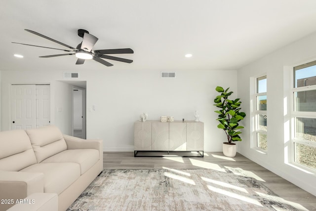 living area with baseboards, light wood-style flooring, visible vents, and recessed lighting