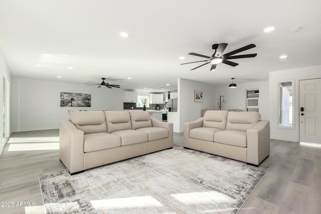 living area with light wood-type flooring, recessed lighting, baseboards, and a ceiling fan