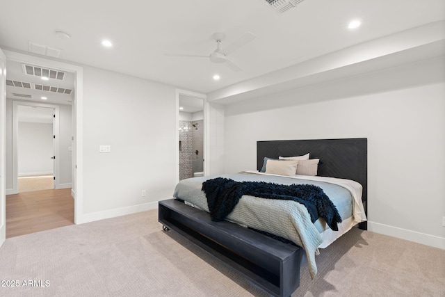 bedroom with ceiling fan, light colored carpet, and ensuite bath