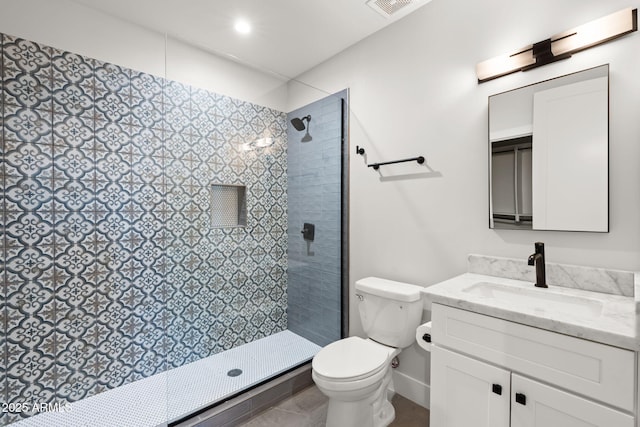 bathroom with vanity, toilet, and a tile shower