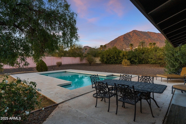 pool at dusk with a mountain view and a patio area