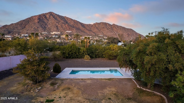 pool at dusk with a mountain view and a patio area