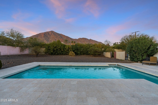 pool at dusk featuring a mountain view and a patio area