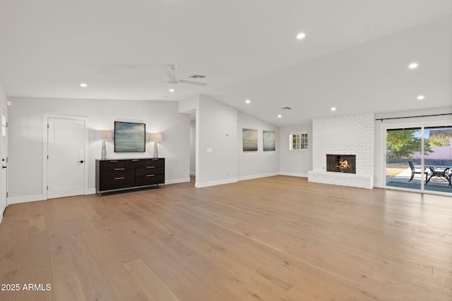 unfurnished living room with light hardwood / wood-style flooring, a fireplace, vaulted ceiling, and ceiling fan