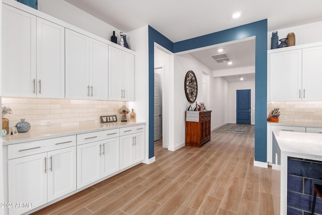 kitchen with light hardwood / wood-style flooring, beverage cooler, decorative backsplash, and white cabinets