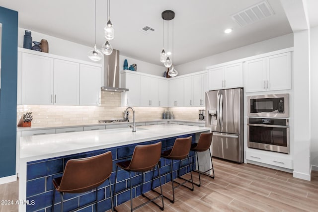 kitchen featuring white cabinets, wall chimney range hood, and stainless steel appliances