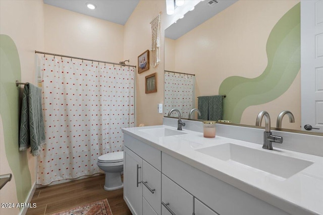 bathroom with hardwood / wood-style flooring, vanity, toilet, and walk in shower