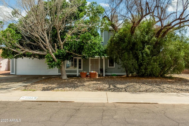 view of property hidden behind natural elements with driveway and an attached garage