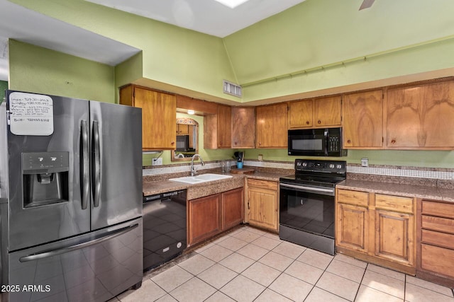kitchen with black appliances, a sink, light tile patterned floors, brown cabinetry, and high vaulted ceiling