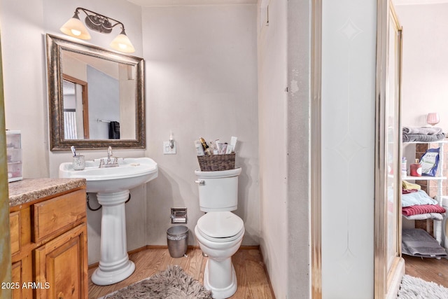bathroom with toilet, wood finished floors, and baseboards