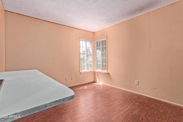 unfurnished bedroom featuring hardwood / wood-style floors, baseboards, and a textured ceiling