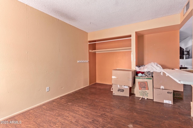 unfurnished bedroom with wood finished floors, a textured ceiling, and baseboards