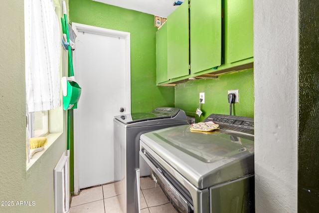 laundry area featuring independent washer and dryer, cabinet space, light tile patterned floors, and a textured wall