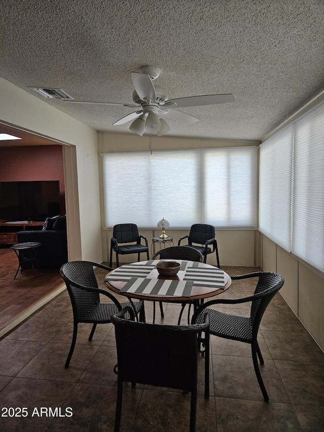 tiled dining area featuring a textured ceiling, visible vents, and ceiling fan