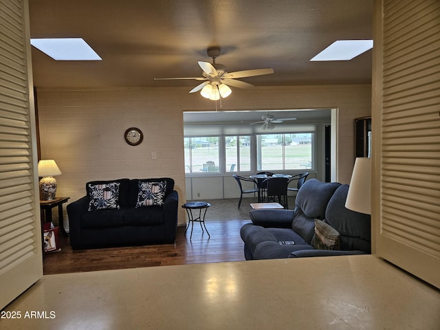 living area featuring wood finished floors, a ceiling fan, and a skylight