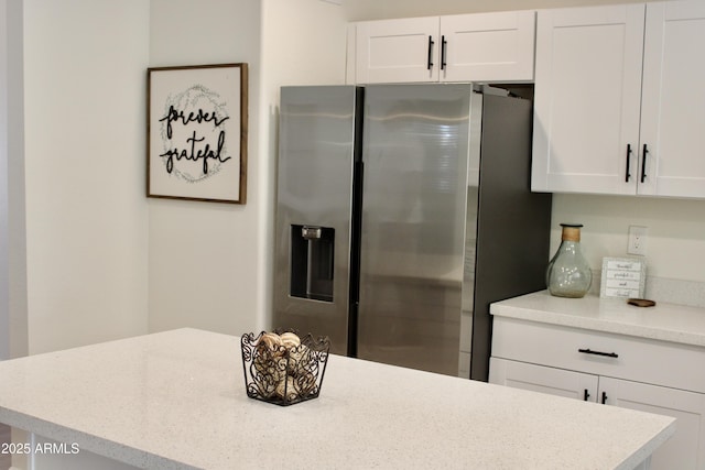 kitchen with light countertops, stainless steel fridge, and white cabinetry