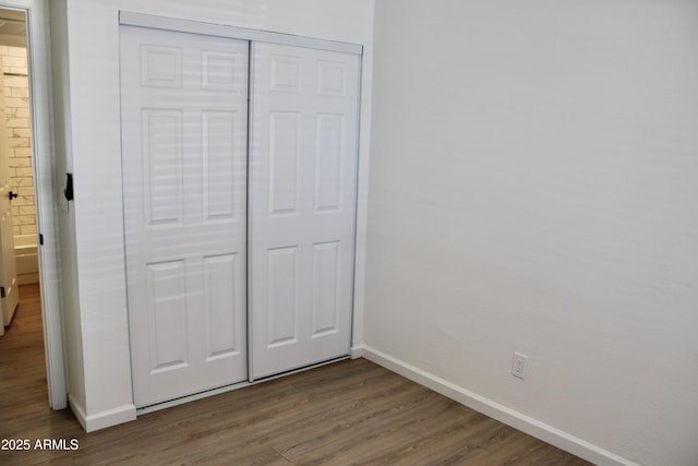 unfurnished bedroom with a closet, baseboards, and wood finished floors