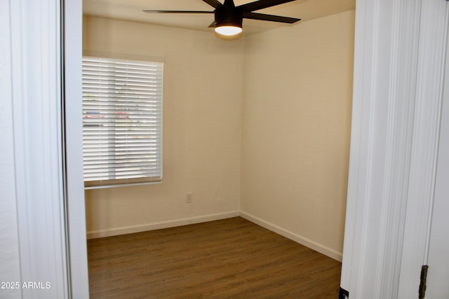 spare room with dark wood-style flooring, a ceiling fan, and baseboards