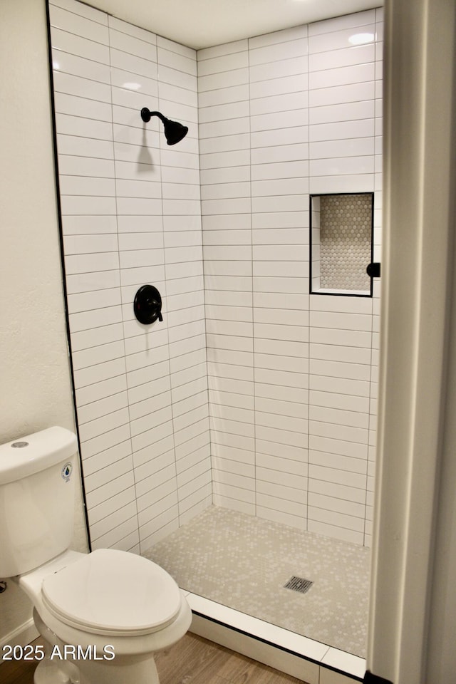 full bathroom with toilet, a stall shower, a baseboard heating unit, and wood finished floors