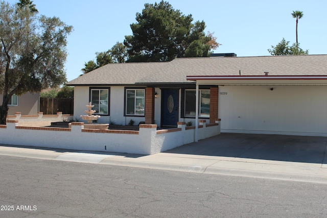 ranch-style home featuring a shingled roof and driveway