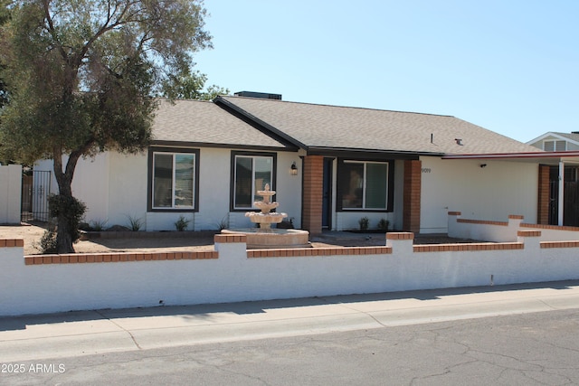 single story home featuring roof with shingles, brick siding, and a fenced front yard