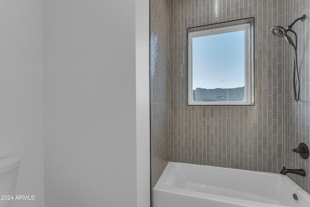 bathroom featuring tiled shower / bath combo and toilet