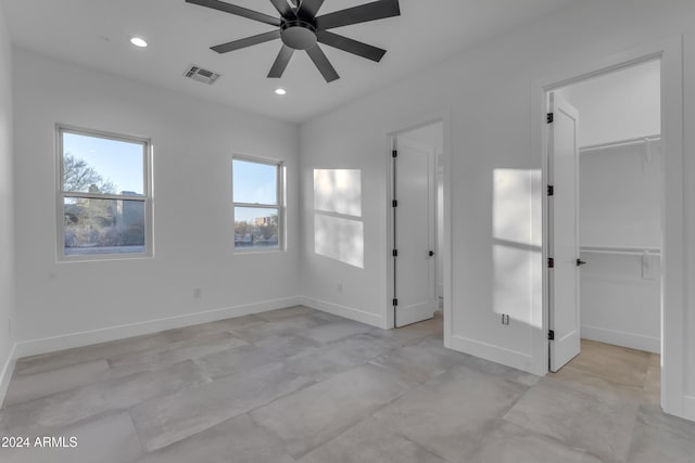 unfurnished bedroom with a closet, a spacious closet, and ceiling fan