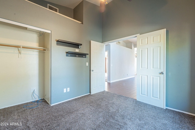 unfurnished bedroom with a closet, carpet flooring, and a high ceiling