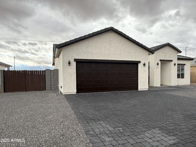 garage with fence and decorative driveway