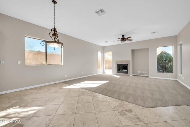 unfurnished living room with light tile patterned flooring, ceiling fan, and a tiled fireplace