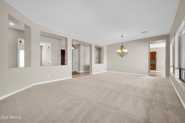 carpeted spare room featuring a notable chandelier