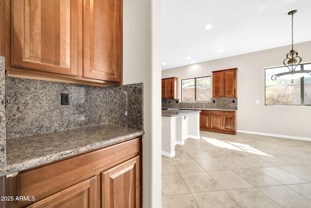 kitchen featuring hanging light fixtures, decorative backsplash, light stone countertops, and light tile patterned flooring