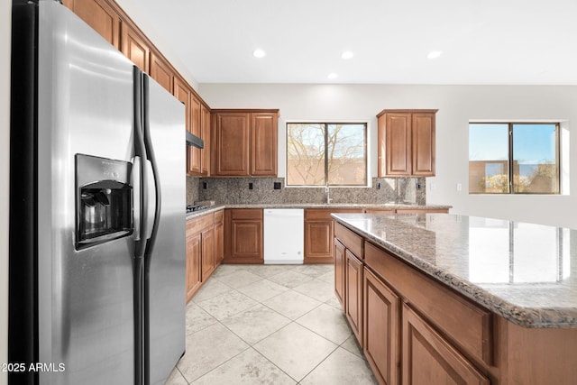 kitchen featuring tasteful backsplash, white dishwasher, light stone countertops, and stainless steel fridge with ice dispenser