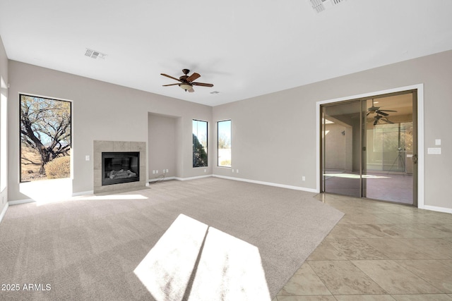 unfurnished living room featuring light colored carpet, a tile fireplace, and ceiling fan