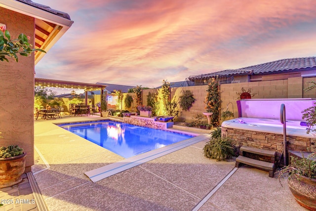 pool at dusk with a jacuzzi and a patio area